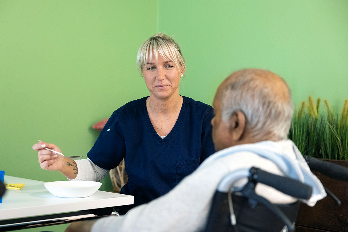 Pflegekraft unterstützt Senior beim Essen in der Seniorenwohnanlage Herzlich & Gerne in Dortmund-Asseln